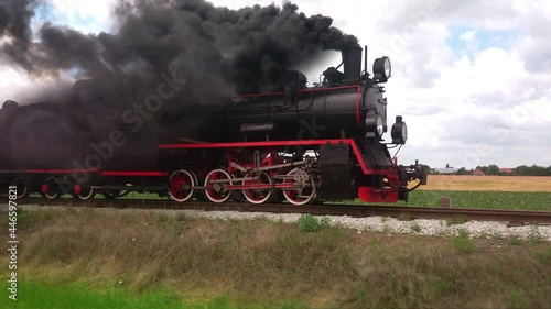 Vintage coal steam locomotive with smoke on trail. Retro transport and travel. Historic train on railroad. photo