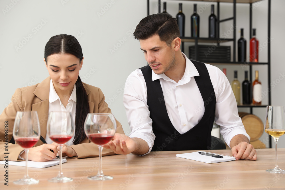 Sommeliers tasting different sorts of wine at table indoors Sommeliers tasting different sorts of wine at table indoors