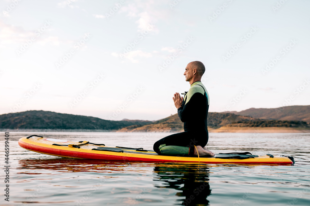 Man practicing yoga on SUP board in sea Man practicing yoga on SUP board in sea