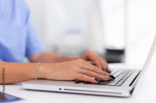 Close up of physician in hospital office typing patient diagnosis. Health practitioner searching in hospital database using laptop in hospital cabinet  keyboard  job.