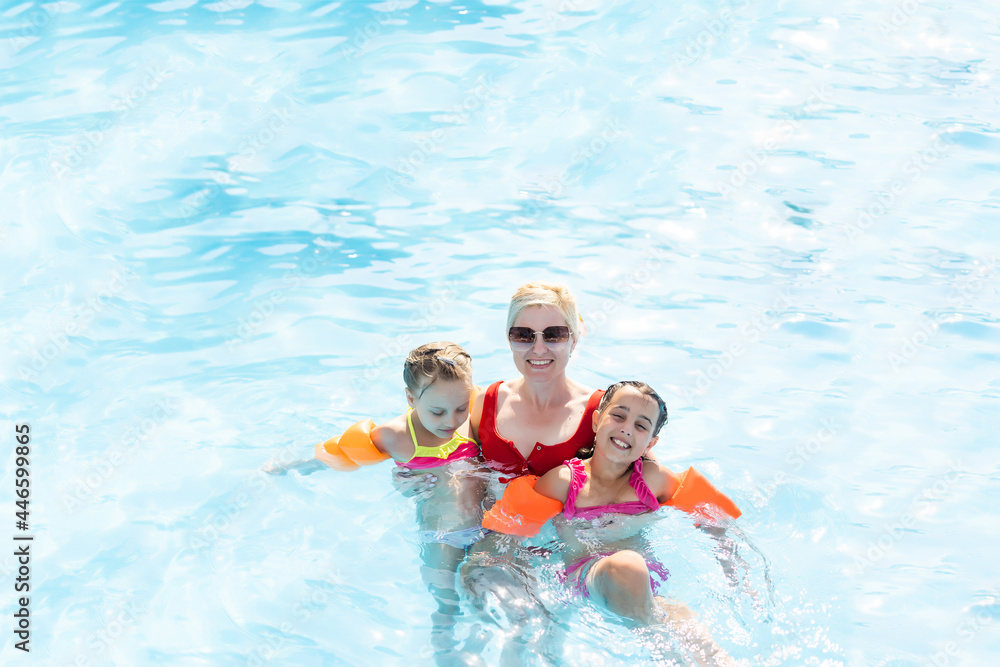 Happy family having fun on summer vacation, playing in swimming pool. Active healthy lifestyle concept