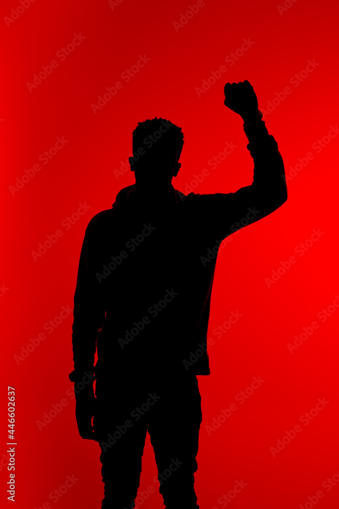 Silhouette of man with raised arm in studio Silhouette of man with raised arm in studio
