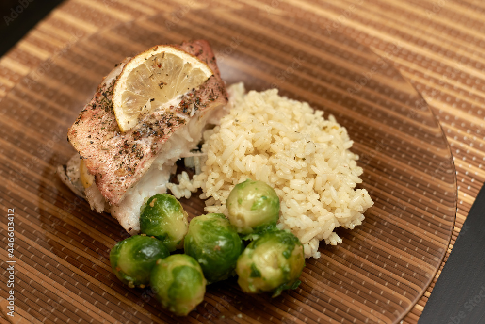 fried sea bass with brussels sprouts and rice on a plate