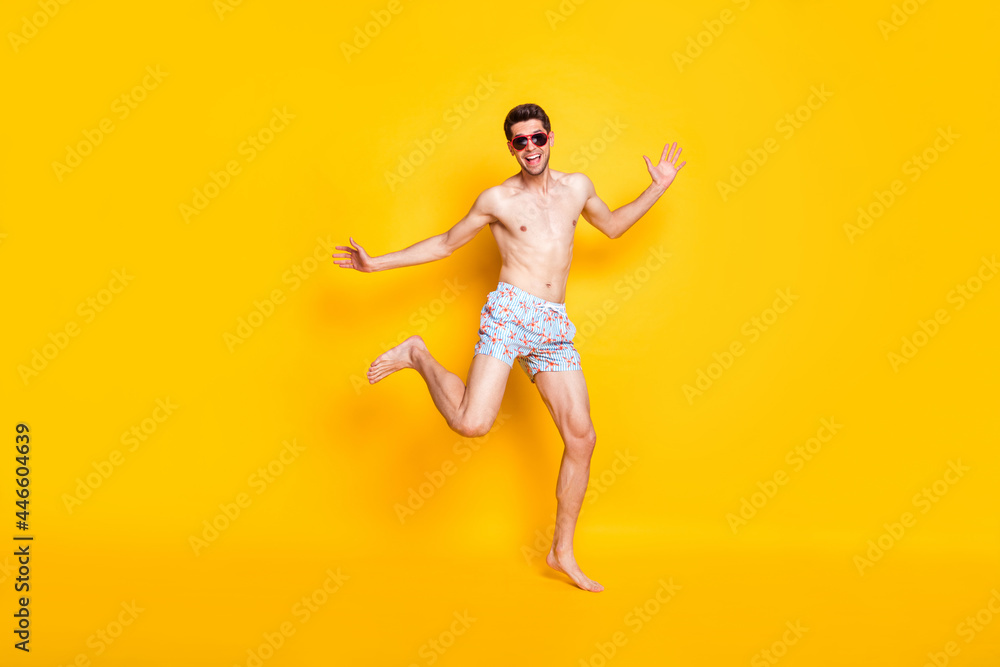Photo of pretty impressed young guy shirtless wear dark glasses smiling dancing isolated yellow color background