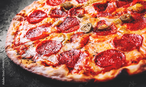 Hot Pepperoni Pizza with Mozzarella cheese, salami, Tomato sauce, pepper, Spices. Italian pizza on Dark grey black slate background