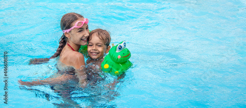 banner with happy brother and sister swim in the pool. Smiling girl and boy are playing in the pool. The concept of family vacation or relaxation in the pool or the sea.