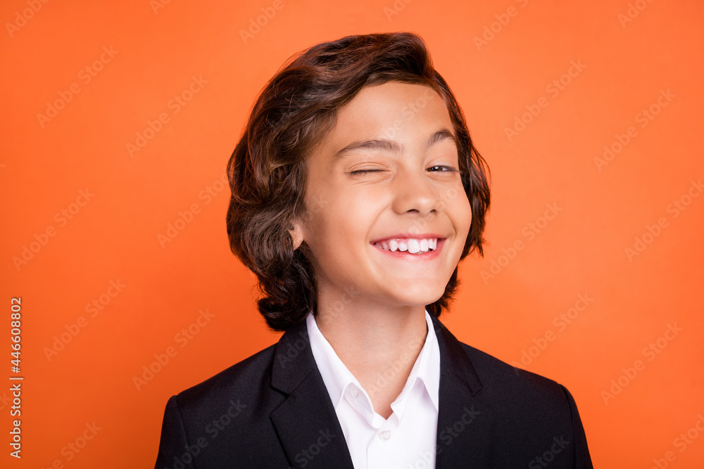 Photo of funky young happy positive little boy wink eye smile good mood enjoy isolated on orange color background Photo of funky young happy positive little boy wink eye smile good mood enjoy isolated on orange color background