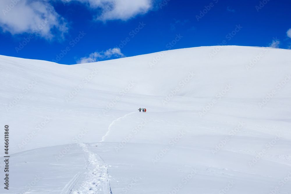 group of snowboarders climbing snow mountain and blue sky