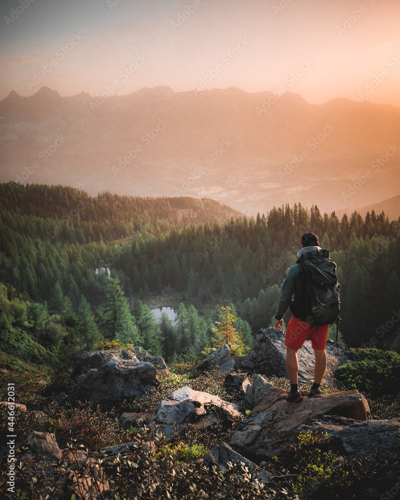 Man standing on a ledge of a mountain, enjoying the View in the Alps of Austria Man standing on a ledge of a mountain, enjoying the View in the Alps of Austria