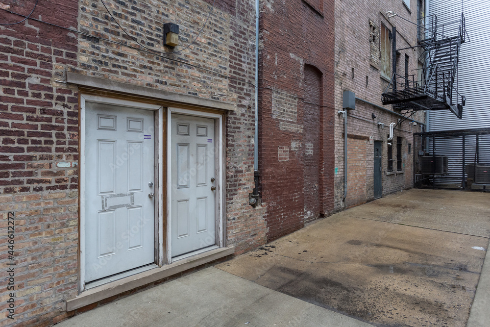 Two dirty white doors on the back of a vintage brick building with steel fire escape Two dirty white doors on the back of a vintage brick building with steel fire escape