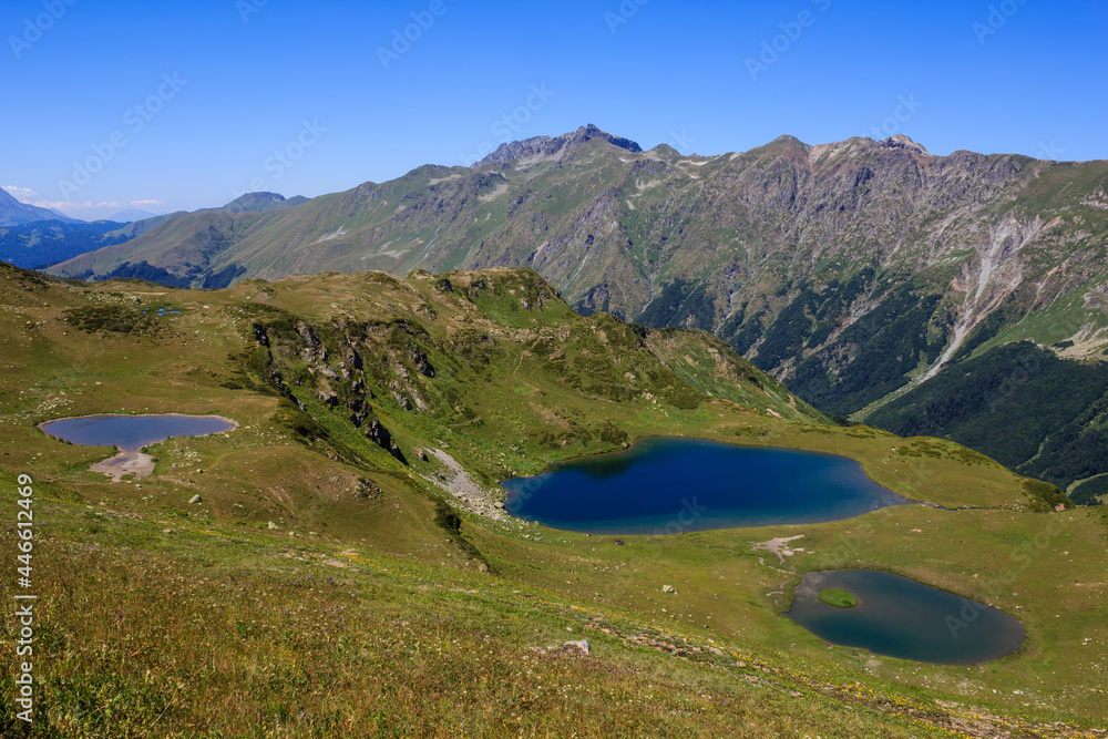 blue mountain lakes in caucasus mountains sorrounded with green grass of alpine meadows
