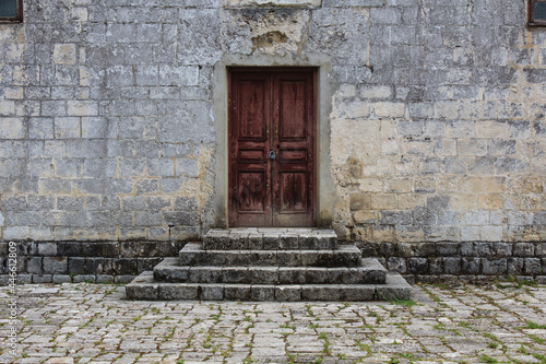 obsolete brown wooden door and with lock stone bricks steps in the front of ancient building