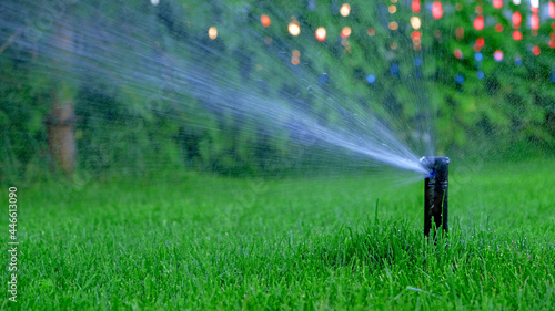 Automatic garden irrigation system watering lawn. Savings of water from sprinkler irrigation system with adjustable head. Automation for lawn irrigation, gardening, soccer fields or golf courses.Bokeh