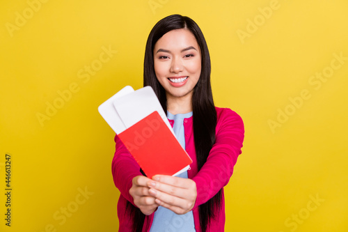 Photo of cheerful young nice positive woman hold hands tickets give you isolated on shine yellow color background