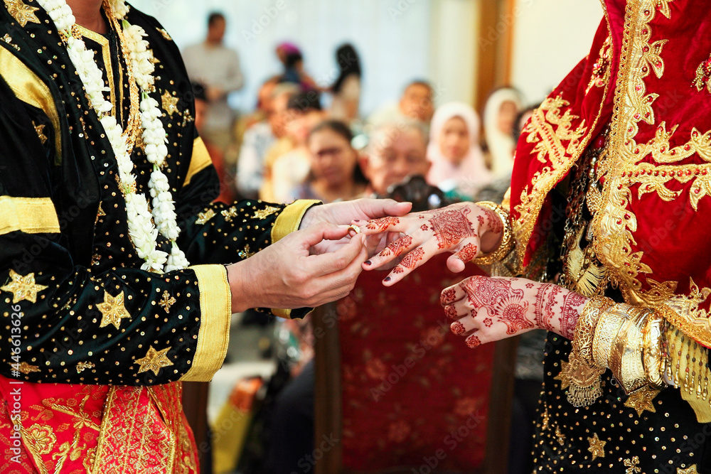 Young Asian muslim couple holding hand and putting wedding ring each other in a traditional minangkabau culture ceremony.