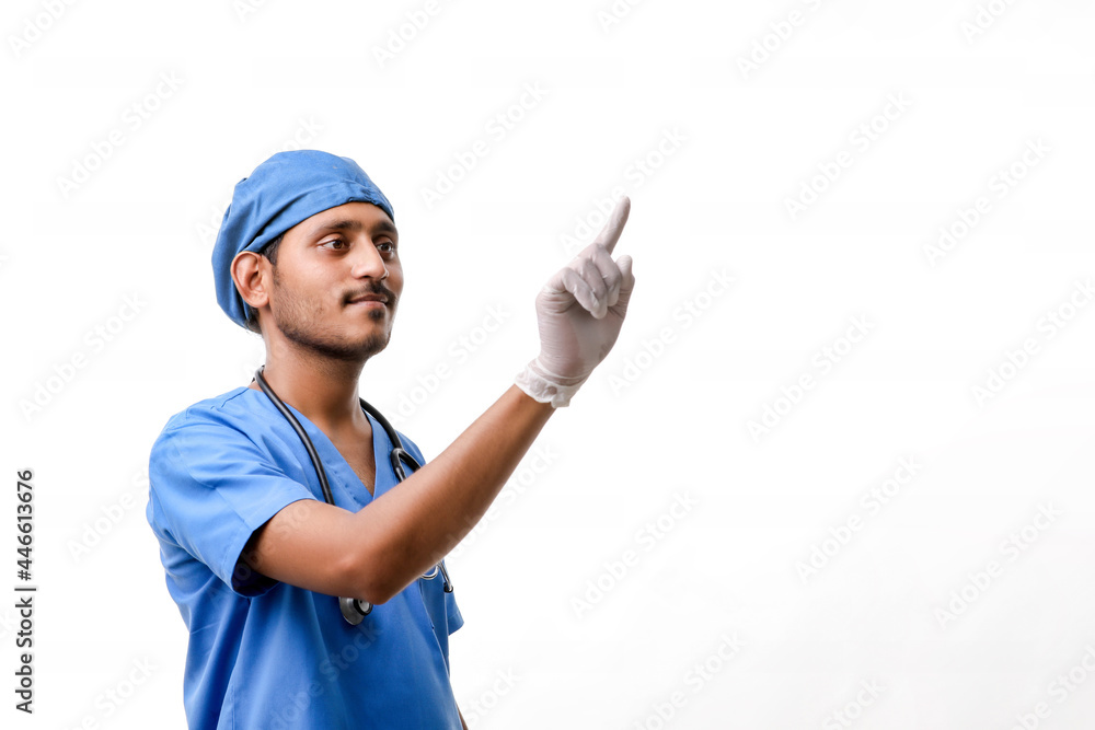 Young indian male doctor pointing with finger over white backgro Young indian male doctor pointing with finger over white backgro