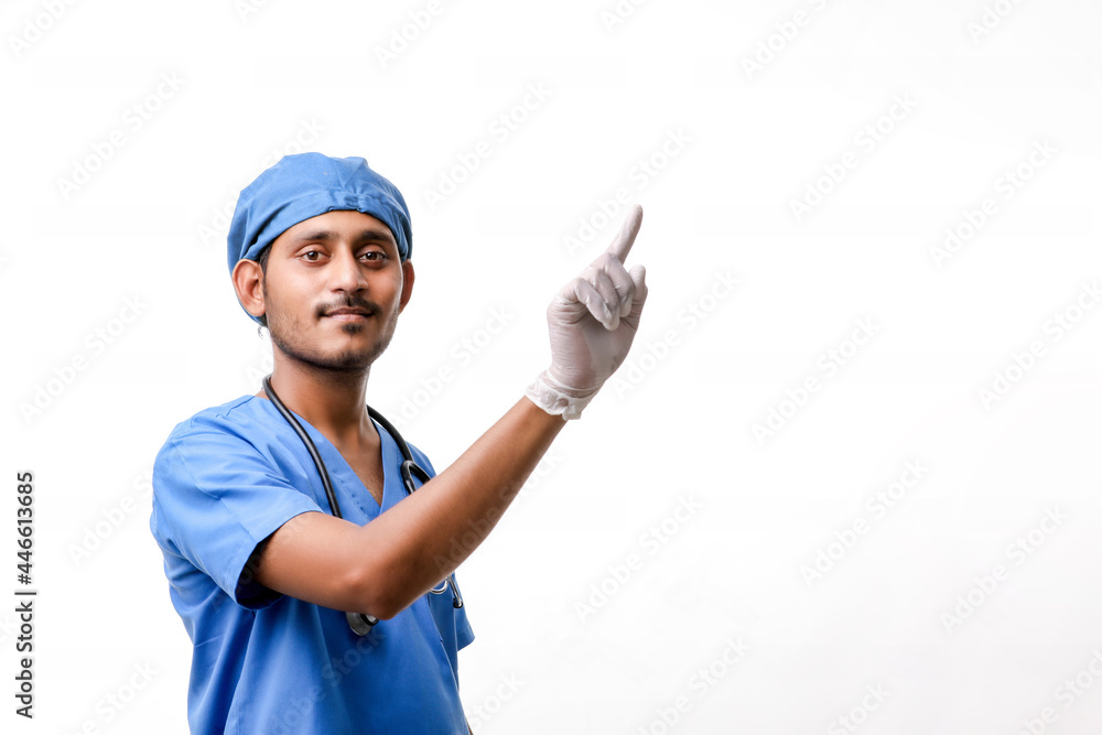 Young indian male doctor pointing with finger over white backgro Young indian male doctor pointing with finger over white backgro
