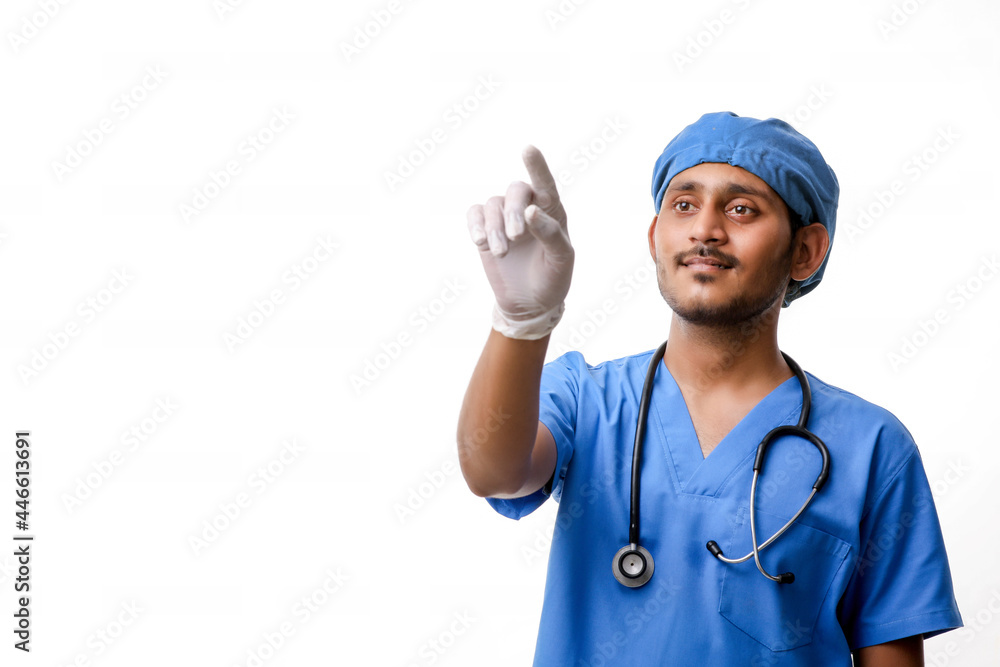 Young indian male doctor pointing with finger over white backgro Young indian male doctor pointing with finger over white backgro