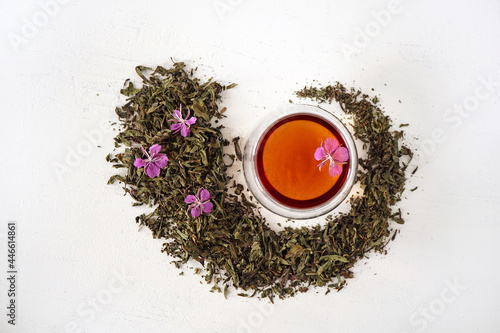  dried willow herb lies in the form of a drop with a cup of tea and a fresh flower in the middle on a white background 