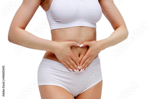Slim woman in white underwear forming a heart symbol with her hands on her belly, isolated on white background