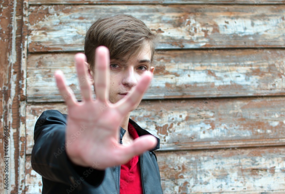 Portrait of seventeen year old guy on blurred background. Youthfulness of facial skin without retouching and makeup. Foreground with outstretched arm in blur