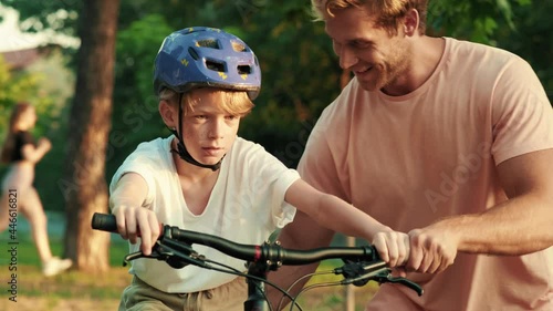 Wallpaper Mural A happy father is helping his young son to ride the bicycle while walking in the park at summer Torontodigital.ca