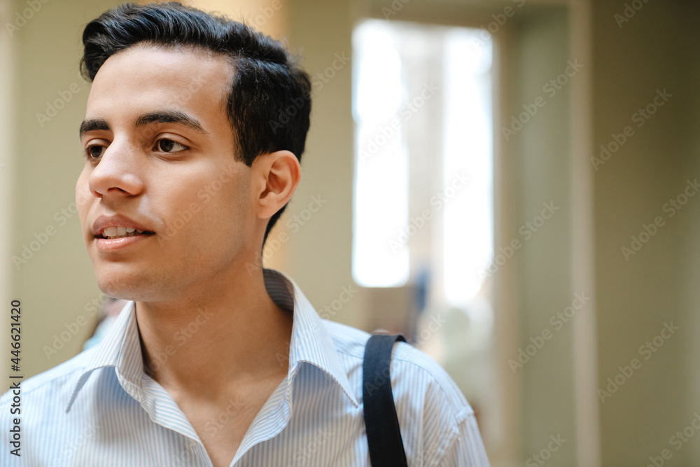 Young middle eastern man looking aside while standing indoors Young middle eastern man looking aside while standing indoors