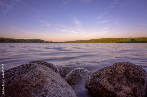 Obraz na płótnie Small boulders submerged in water of a lake on a lakeshore at dusk w salonie
