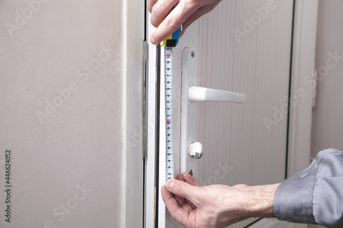 Caucasian man measuring door in room.