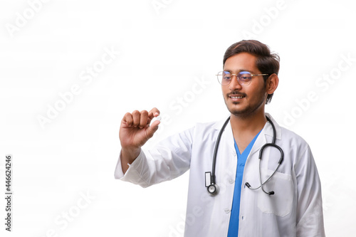 Young indian doctor holding pill in hand.