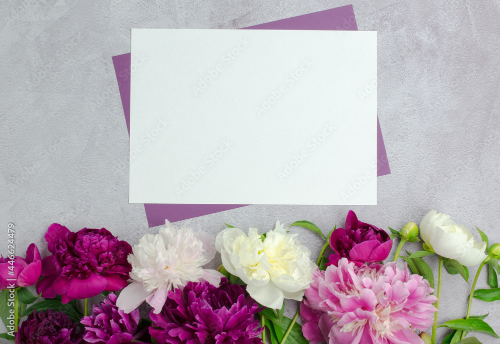 A clean sheet of paper with peony flowers on a concrete background. Blank for a greeting card or invitation, mock-up A clean sheet of paper with peony flowers on a concrete background. Blank for a greeting card or invitation, mock-up