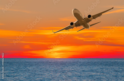 Airplane flying over tropical sea at sunset © muratart