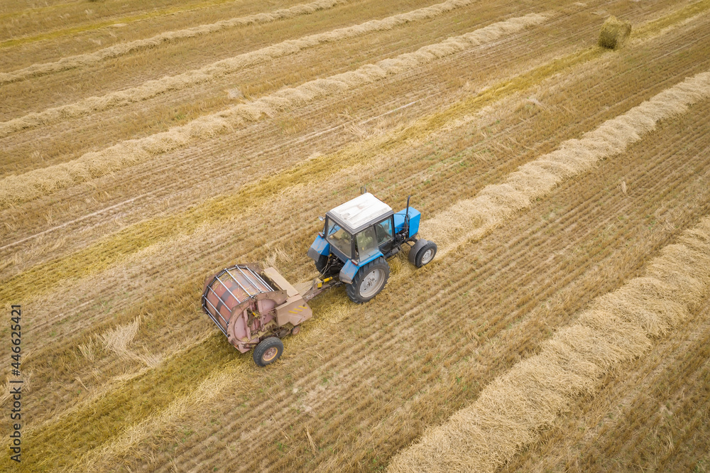 A tractor with a trailer aerial view. Harvesting from the field. Dry straw collection trailer.