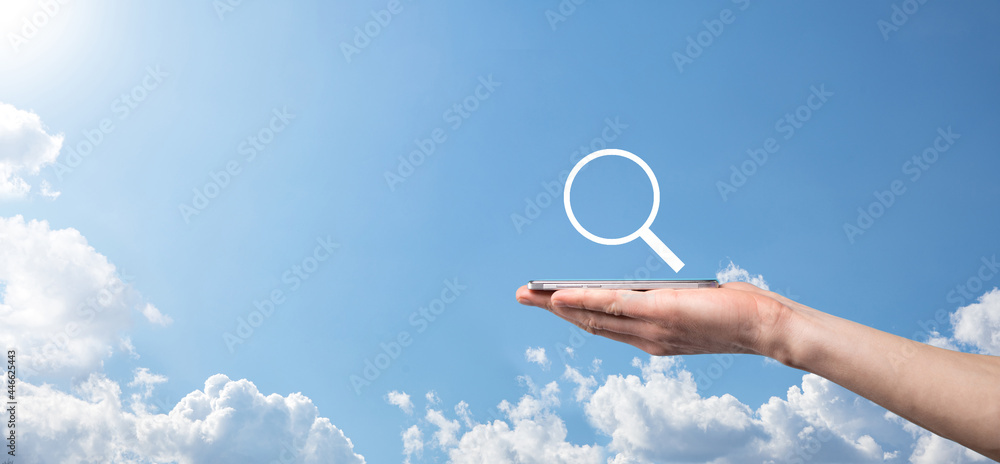 Male hand holding magnifying glass ,search icon on blue background. Concept search engine optimization, customer support.Browsing Internet Data Information.Networking Concept. Male hand holding magnifying glass ,search icon on blue background. Concept search engine optimization, customer support.Browsing Internet Data Information.Networking Concept.
