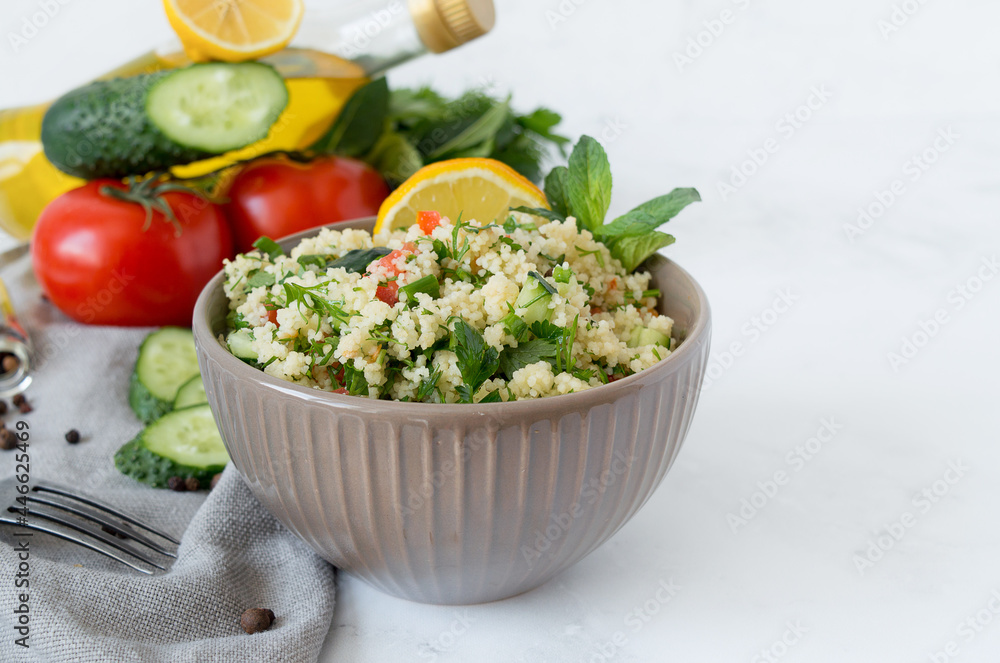 Traditional oriental salad Tabouleh with couscous or bulgur on a white marble background. Traditional oriental salad Tabouleh with couscous or bulgur on a white marble background.