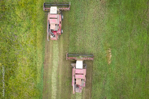 Obraz na płótnie Top view of two tractors. The seasonal works in the field. Machines are mowing grass for farms. w salonie