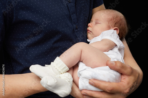 Close up view of mens hand holds a little newborn baby isolated on black background