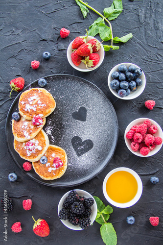 A healthy breakfast of cheese pancakes, berries, and honey. Creative atmospheric decoration