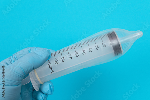 Safe Vaccine, Anti Vaccination Concept - Syringe in a Condom Holds in a Hand with Medical Glove. Mistrust of Vaccination. Natural Immunity. Skepticism About the Vaccine. Freedom and Human Rights photo