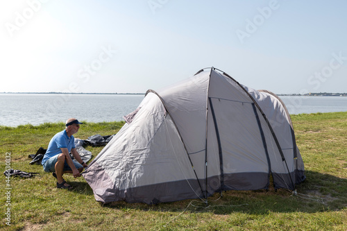 man setting up a tent at the waterline