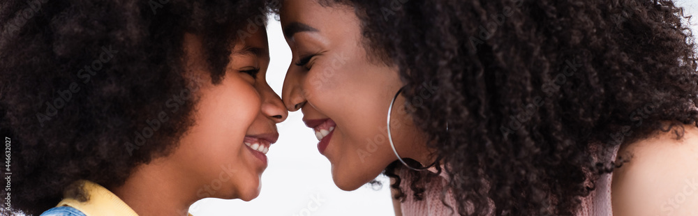 Obraz premium Side view of african american mother and daughter standing nose to nose isolated on white, banner