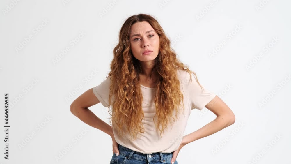 A serious displeased woman is doing stop gesture while crossing her arms isolated over a white wall in the studio A serious displeased woman is doing stop gesture while crossing her arms isolated over a white wall in the studio