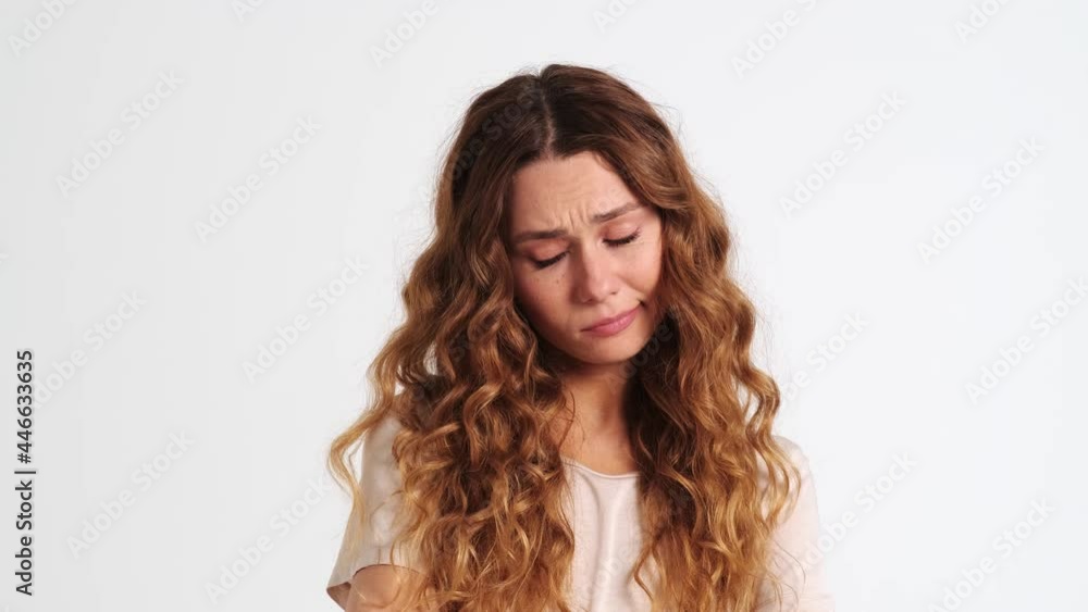 An offended woman is crying standing isolated over a white wall in the studio An offended woman is crying standing isolated over a white wall in the studio