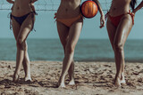Portrait of Three Young Women in bikini Standing by a Volleyball Net on the beach