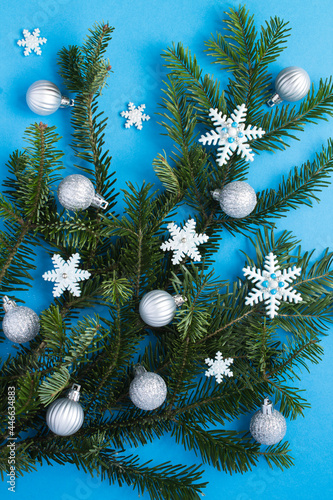 Close-up on christmas composition with spruce branches, silver balls and snowflakes on the blue background