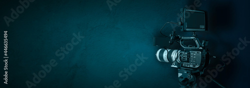Video camera on dark blue background with copy space. Movie production, commercial film or broadcasting banner.