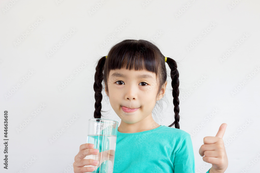 asian child with pigtails hair style hold a glass of water and lick her lips asian child with pigtails hair style hold a glass of water and lick her lips