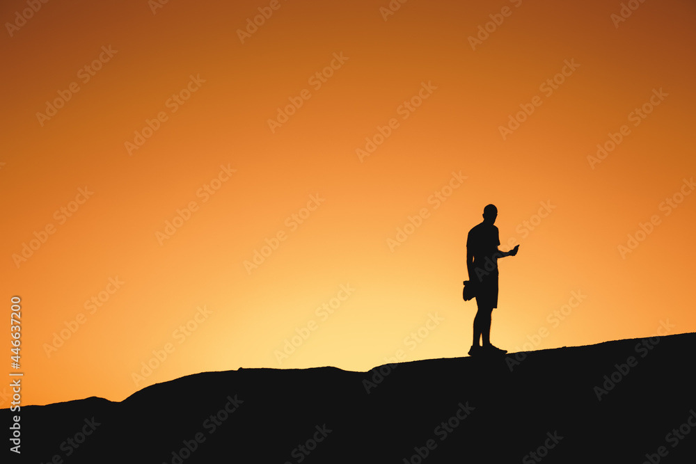 Silhouette of a man standing on a mountain at sunset
