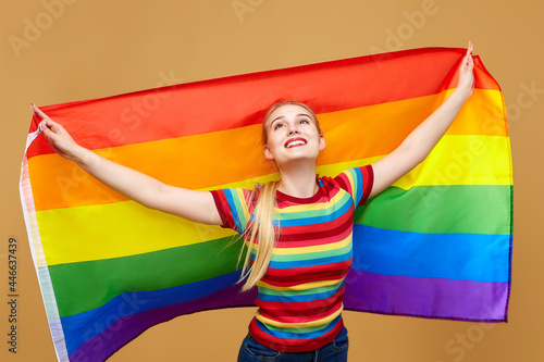 attractive blonde made posing with a rainbow LGBT flag. photo shoot in the studio on a yellow background
