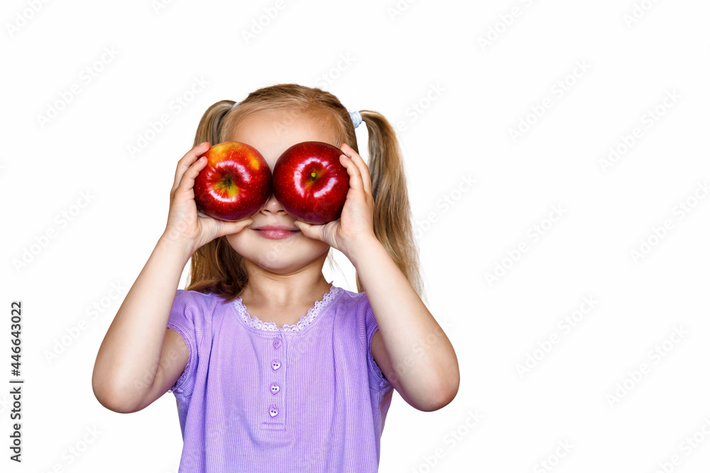 Little girl on a white background holds apples in his hands. The child holds two red apples in front of her eyes Little girl on a white background holds apples in his hands. The child holds two red apples in front of her eyes
